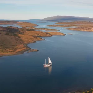 Navegación Paso Guaraní – 3 días y 2 noches a bordo del Velero Ksar Desde Ushuaia hacia el corazón del Canal Beagle y el Paso Guaraní Viví una travesía inolvidable de 3 días y 2 noches navegando desde Ushuaia hacia Puerto Almanza, a bordo del Velero Ksar, en una expedición única por el Canal Beagle, con pernocte en lugares remotos, observación de fauna y paisajes inigualables en el Fin del Mundo. Itinerario Detallado Día 1: Isla de los Lobos y Faro Les Éclaireurs Zarpamos desde Ushuaia a las 8:30 AM rumbo a la Isla de los Lobos, donde se pueden observar lobos marinos de dos pelos en su hábitat natural. Luego navegamos hacia el icónico Faro Les Éclaireurs, ideal para fotografía y avistaje de aves del canal como cormoranes imperiales, gaviotas, cauquenes y petreles. Almuerzo a bordo y llegada por la tarde a la Estancia Remolino. Cena a bordo y noche fondeados. Día 2: Paso Guaraní e Isla Martillo Después del desayuno, navegamos rumbo este hacia Puerto Almanza, cruzando el impresionante Paso Guaraní. El entorno natural es impactante. Llegamos a Isla Martillo para avistar pingüinos Papúa (Yantu). Almuerzo en navegación. Cena y pernocte fondeados en una caleta protegida de Paso Guaraní. Día 3: Regreso a Ushuaia Después del desayuno, comenzamos el regreso con una llegada estimada a Ushuaia a las 18:30 hs. Especificaciones del Viaje Duración: 3 días / 2 noches Máximo con hotelería: 4 navegantes Mínimo con hotelería: 4 navegantes Para menos navegantes en navegación privada, el costo es el equivalente a 4 tickets Servicios Incluidos Desayuno, almuerzo, merienda, cena y bebidas Cena a bordo bajo las estrellas Navegación completa con fondeo en lugares protegidos Tripulación profesional Transporte terrestre desde Puerto Almanza en caso de que las condiciones meteorológicas impidan el retorno por mar (para garantizar conexiones aéreas o actividades programadas) Importante Nuestro servicio está condicionado por la naturaleza. Todas las navegaciones están sujetas a las condiciones climáticas, por lo tanto, el itinerario puede variar o cancelarse ante situaciones adversas. Las decisiones se toman en tiempo real durante la navegación, priorizando la seguridad. ¿Qué llevar a bordo? Te recomendamos consultar el equipo necesario para navegar, incluyendo ropa impermeable, abrigo térmico, calzado adecuado y accesorios esenciales para tu confort en mar. Una experiencia única en el Fin del Mundo Explorá el Paso Guaraní y la costa más oriental de Tierra del Fuego en una expedición íntima y profunda por el Canal Beagle. Navegación, avistajes, trekking, estrellas, pingüinos y silencio. Una travesía para reconectar con la naturaleza salvaje y descubrir un rincón remoto del sur austral. Consultar costos Escribinos a: info@veleroksar.com Más información en: www.veleroksar.com
